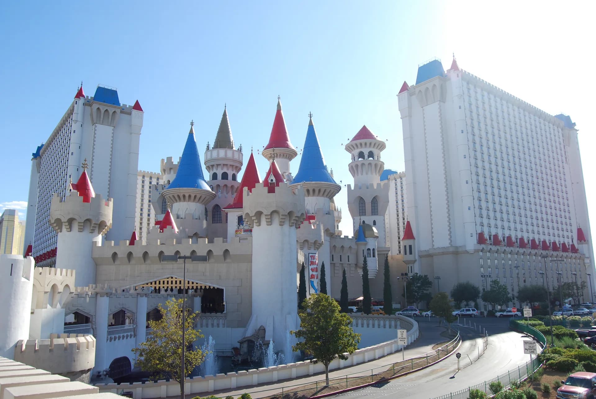 Daytime wide view of Excalibur Hotel & Casino’s castle-style exterior, with colorful pointed turret roofs and hotel towers in Las Vegas.