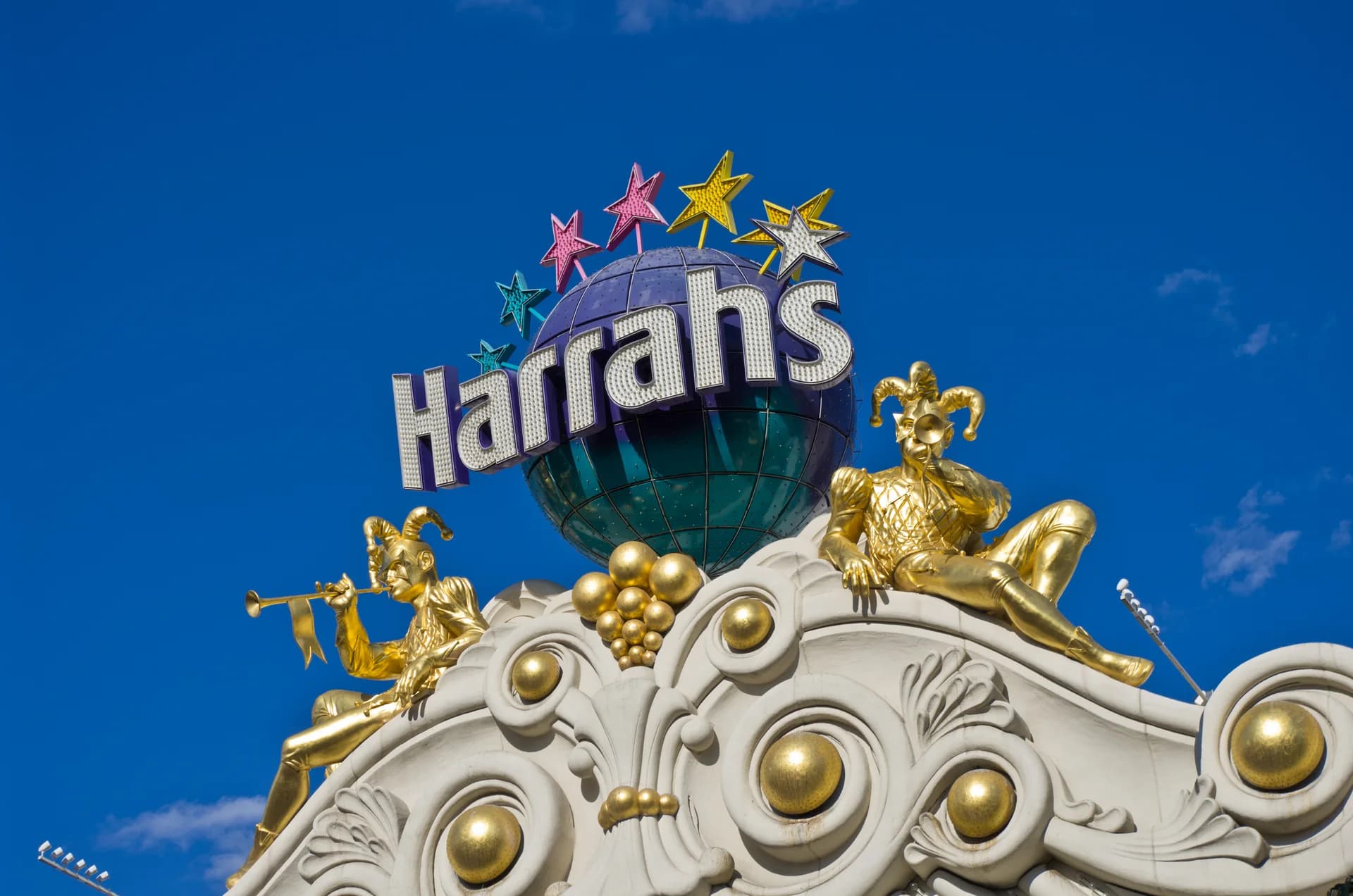 Harrah's Las Vegas globe sign and carnival-themed facade against a blue sky; this is the host-property frontage for Carnaval Court.