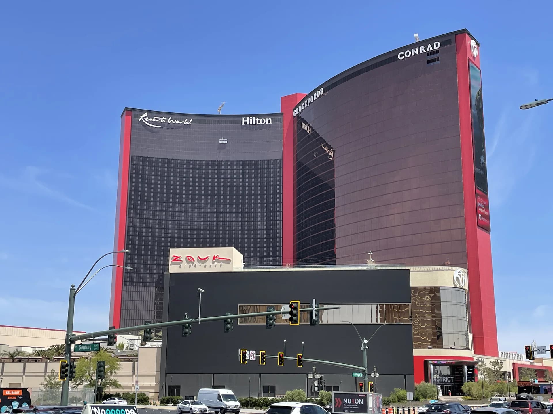 Daytime view of Resorts World Las Vegas’ red hotel towers from Las Vegas Boulevard; the building contains the public-space art walk.