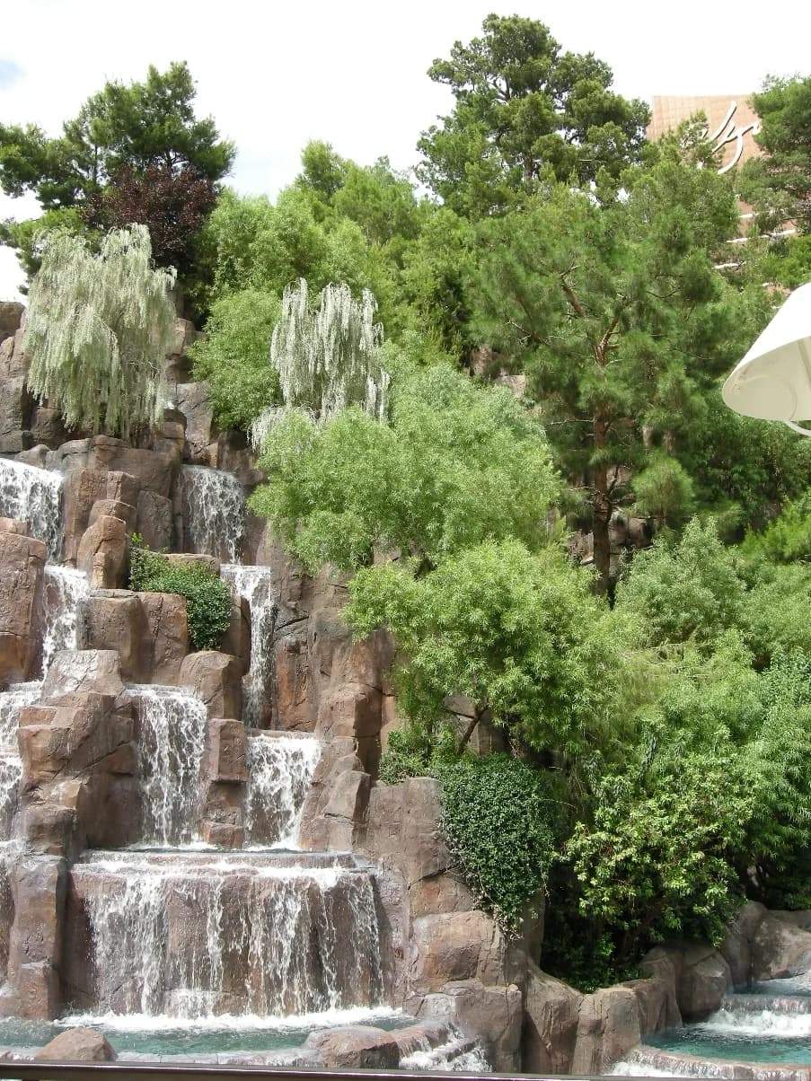 Artificial waterfall at Wynn Las Vegas’s Lake of Dreams, framed by greenery and rockwork.